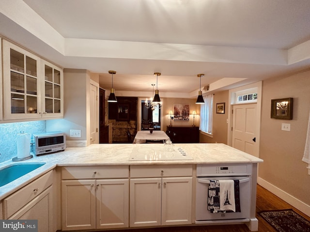 kitchen featuring a tray ceiling, black electric cooktop, pendant lighting, and dark wood-type flooring