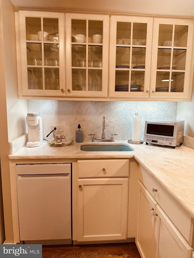 bar featuring backsplash, dishwashing machine, and sink