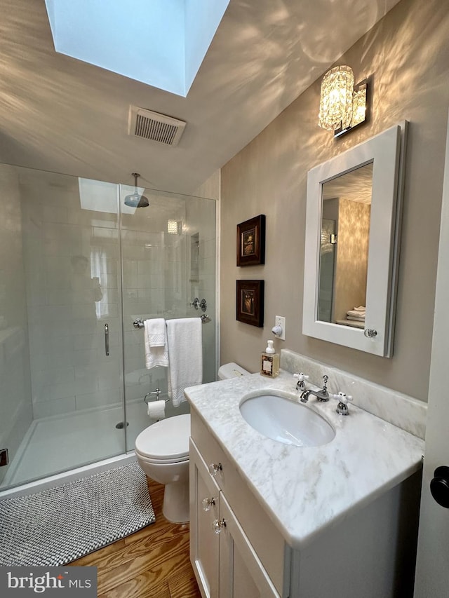 bathroom with vanity, vaulted ceiling, toilet, an enclosed shower, and wood-type flooring