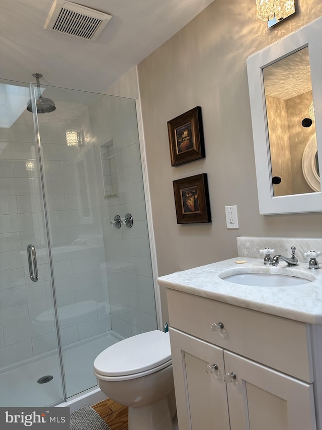 bathroom with wood-type flooring, vanity, toilet, and a shower with shower door