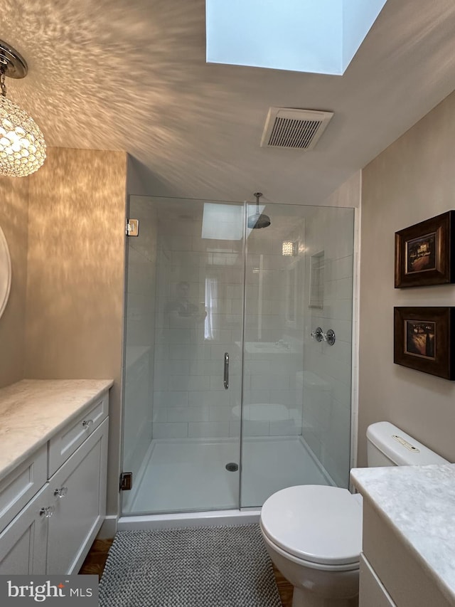 bathroom featuring a skylight, vanity, and a shower with shower door