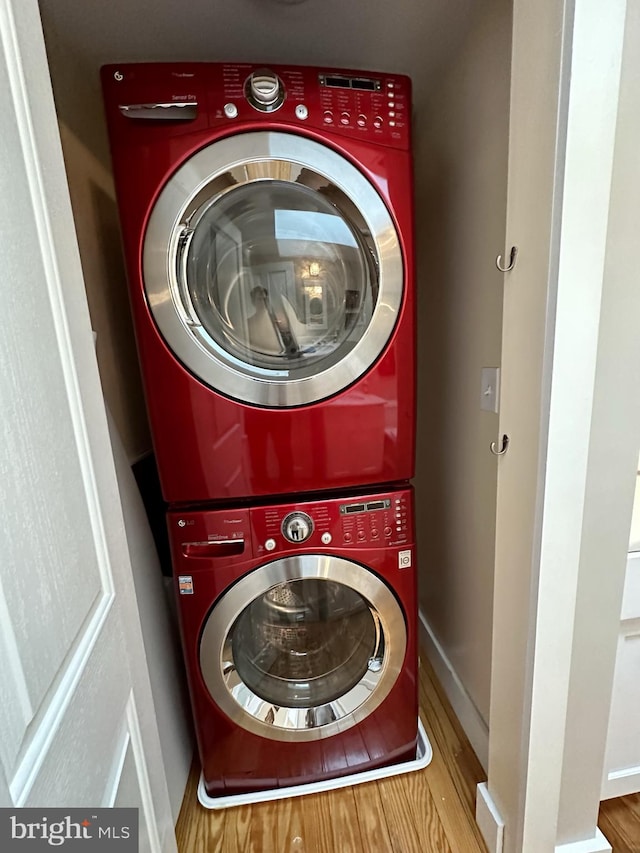 clothes washing area with hardwood / wood-style floors and stacked washer and clothes dryer