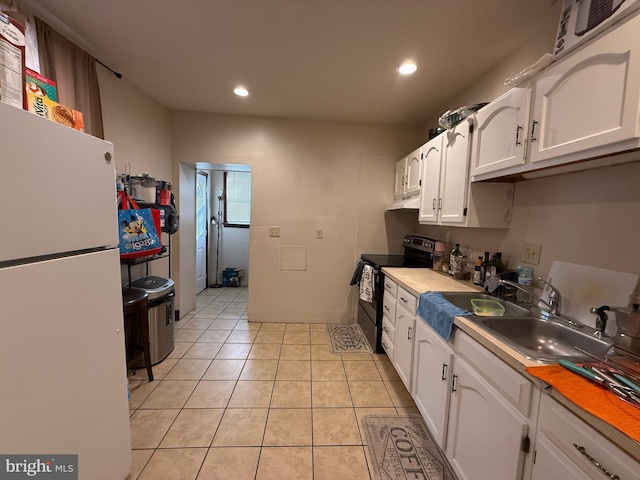 kitchen featuring black electric range, light tile patterned floors, white refrigerator, and white cabinetry