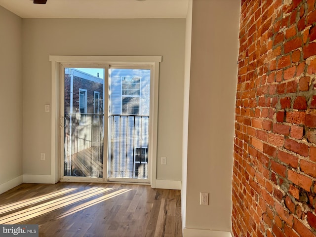 doorway featuring hardwood / wood-style floors and brick wall