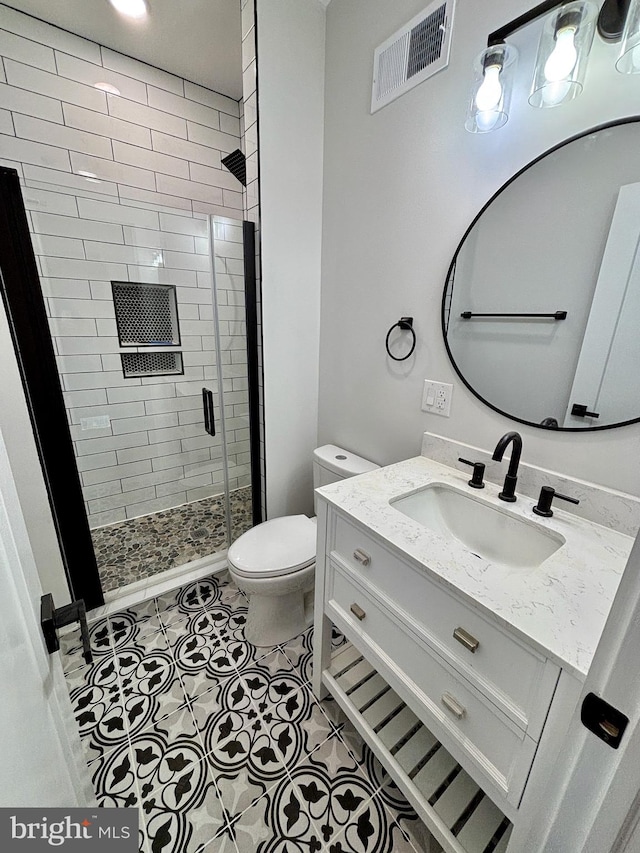 bathroom featuring tile patterned flooring, vanity, toilet, and an enclosed shower