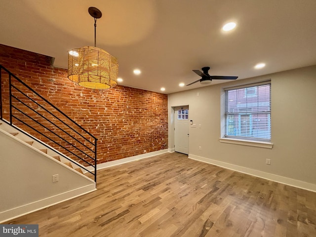 entrance foyer featuring ceiling fan, hardwood / wood-style floors, and brick wall