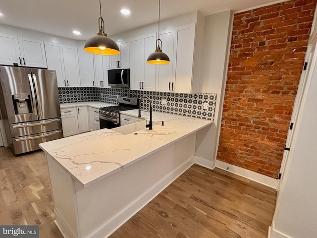 kitchen featuring kitchen peninsula, white cabinetry, hanging light fixtures, and appliances with stainless steel finishes