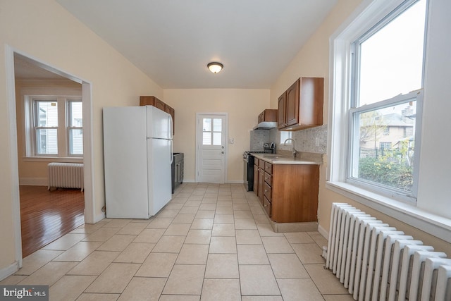 kitchen with radiator heating unit, white fridge, and a healthy amount of sunlight