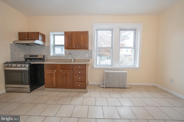 kitchen featuring backsplash, a wealth of natural light, radiator heating unit, and stainless steel stove