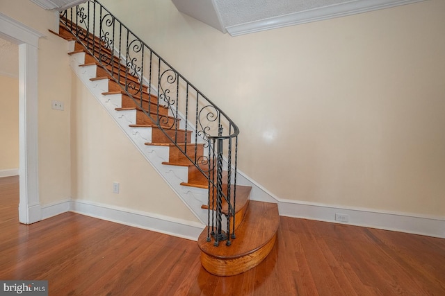 stairs featuring hardwood / wood-style floors and ornamental molding