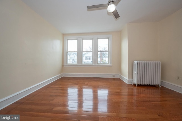 empty room featuring ceiling fan, dark hardwood / wood-style flooring, and radiator heating unit