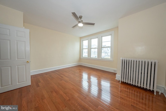 unfurnished room featuring radiator, ceiling fan, and hardwood / wood-style flooring