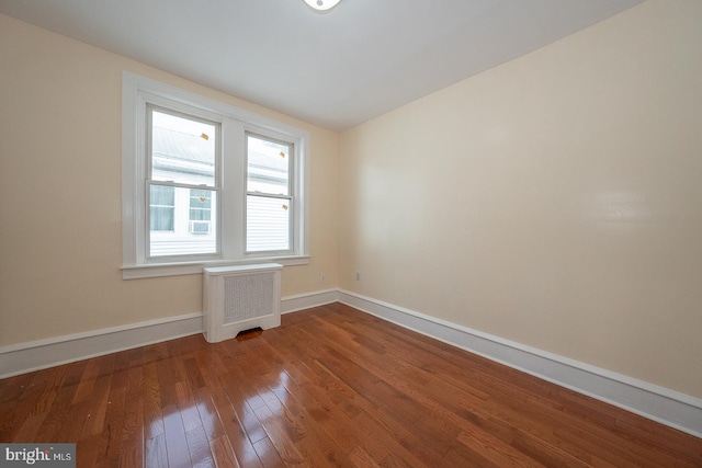 empty room with hardwood / wood-style floors and radiator