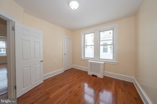 empty room with radiator, a wealth of natural light, and wood-type flooring