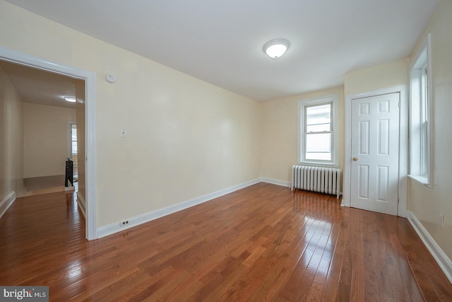 spare room with dark hardwood / wood-style floors and radiator