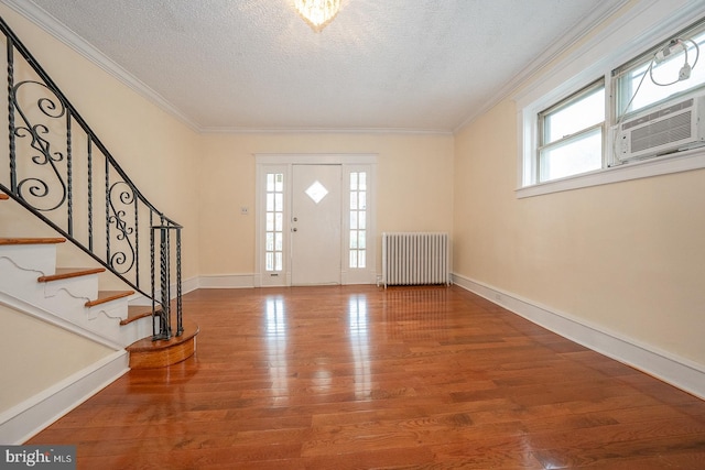 foyer featuring radiator, hardwood / wood-style floors, a healthy amount of sunlight, and a textured ceiling