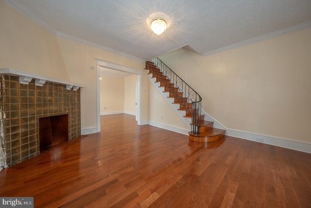 unfurnished living room featuring a fireplace, a textured ceiling, hardwood / wood-style flooring, and ornamental molding