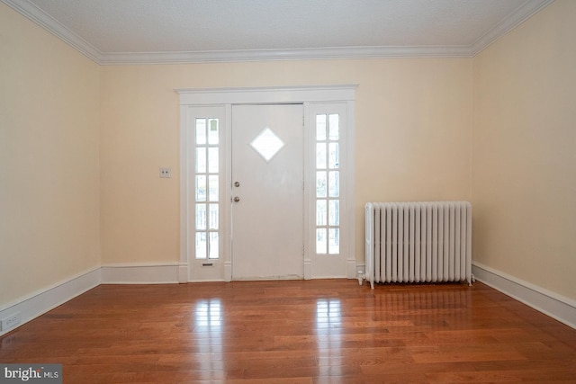 foyer entrance featuring a textured ceiling, hardwood / wood-style flooring, radiator, and ornamental molding