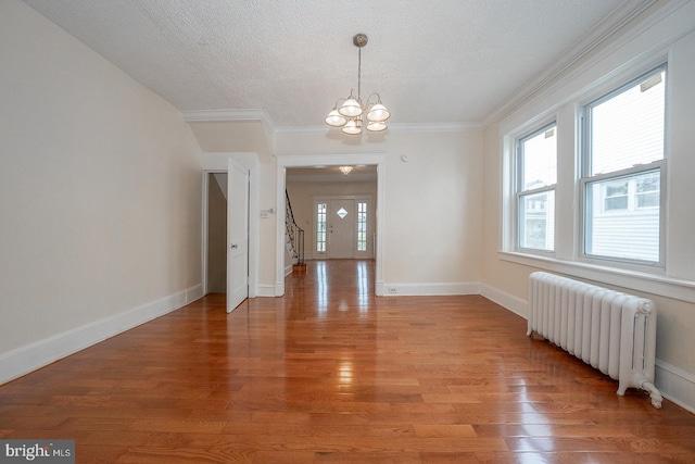 unfurnished dining area with radiator, light hardwood / wood-style floors, and a textured ceiling