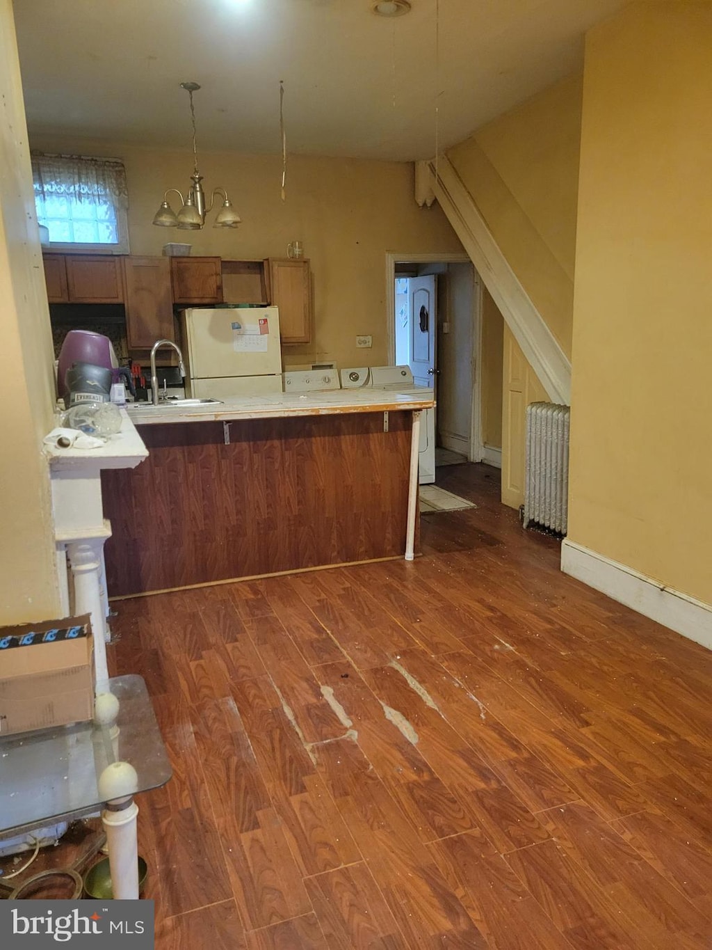 kitchen with dark wood-type flooring, sink, radiator heating unit, white fridge, and kitchen peninsula