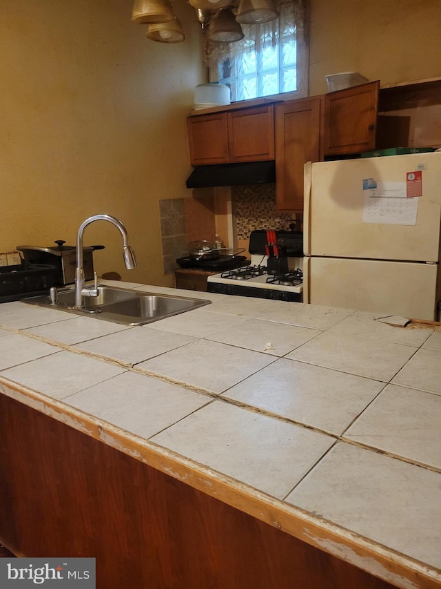 kitchen with tile countertops, decorative backsplash, white appliances, and sink