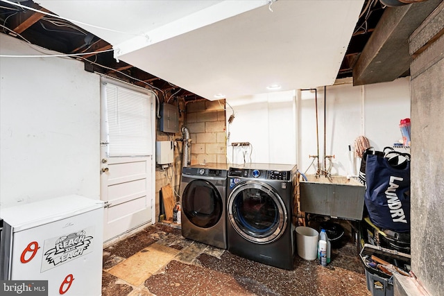 clothes washing area with sink, electric panel, and washing machine and clothes dryer