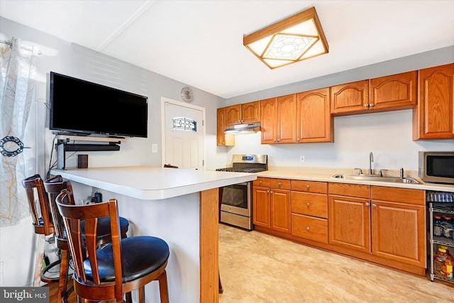 kitchen with sink, wine cooler, kitchen peninsula, a breakfast bar area, and appliances with stainless steel finishes