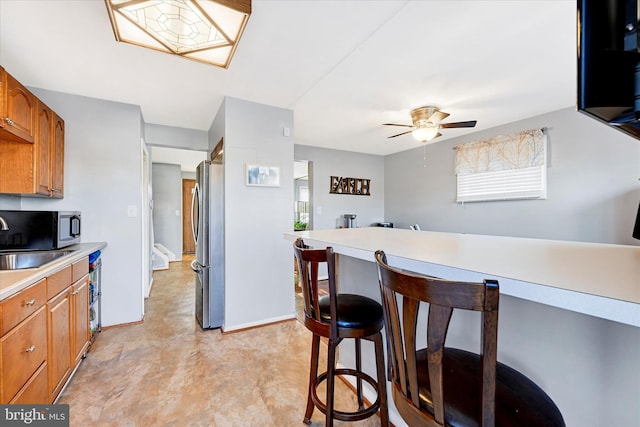 kitchen featuring ceiling fan, sink, stainless steel appliances, and a breakfast bar