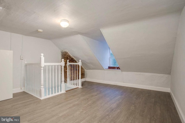 bonus room featuring vaulted ceiling with skylight and hardwood / wood-style flooring