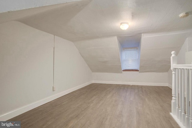 additional living space featuring hardwood / wood-style flooring and lofted ceiling