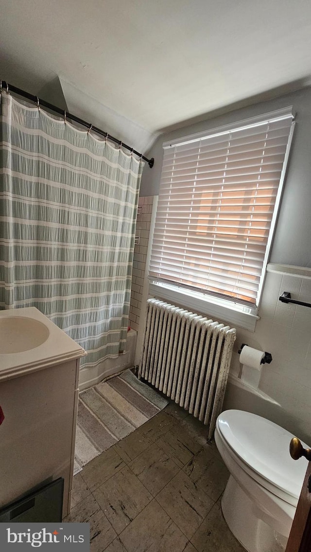 full bathroom with radiator, shower / bath combo with shower curtain, vanity, and toilet