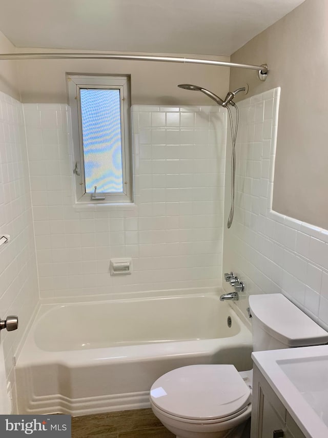 full bathroom with vanity, tiled shower / bath combo, tile walls, and toilet