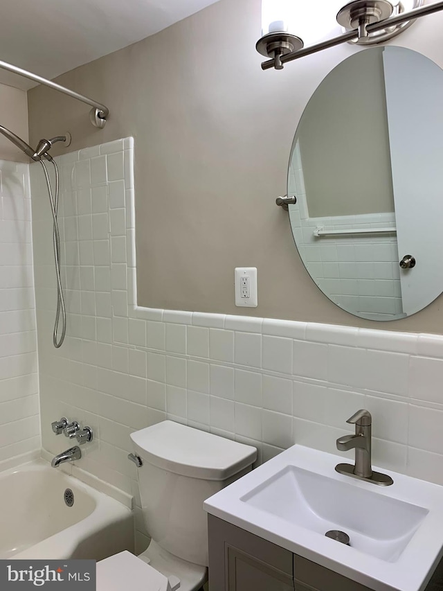 full bathroom with vanity, tiled shower / bath combo, toilet, and tile walls