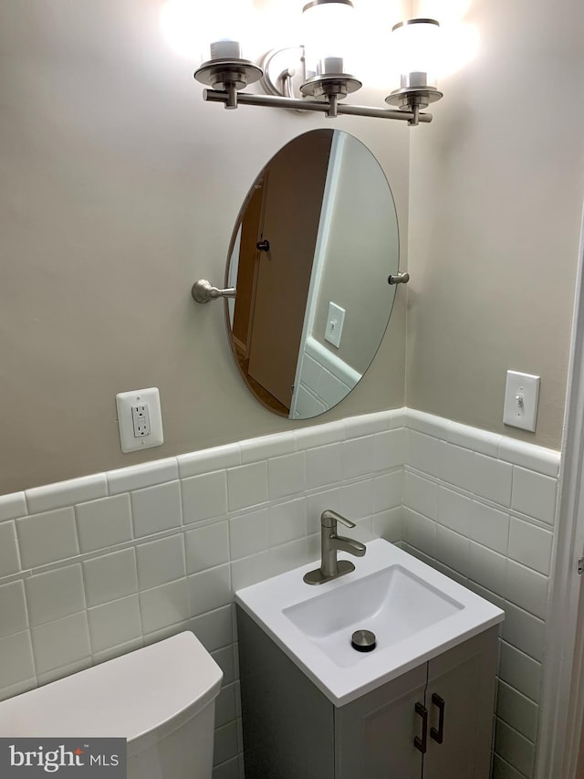 bathroom featuring vanity, toilet, and tile walls