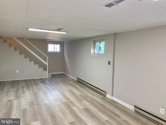 basement featuring baseboard heating and light hardwood / wood-style flooring