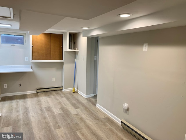 basement featuring light wood-type flooring and a baseboard radiator