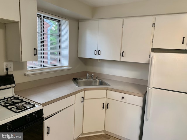 kitchen with sink, white cabinets, white appliances, and light wood-type flooring