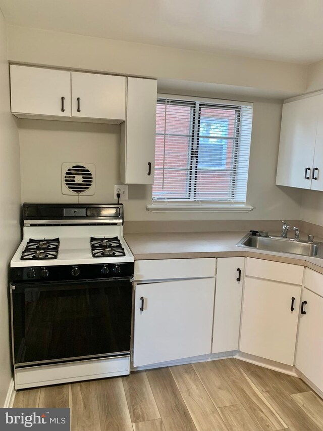 kitchen with sink, white cabinetry, and white gas range oven