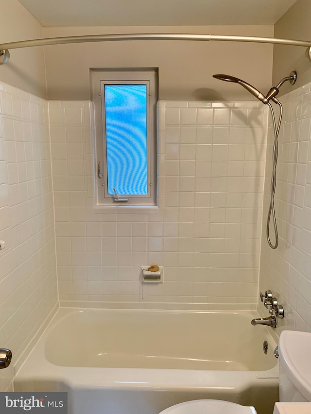 bathroom with tiled shower / bath combo and toilet