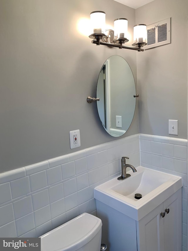 bathroom with vanity, toilet, and tile walls