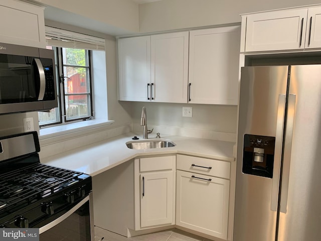 kitchen with appliances with stainless steel finishes, white cabinetry, and sink