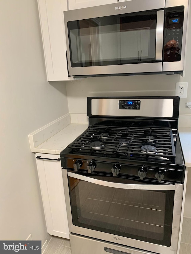 room details featuring white cabinetry, light stone countertops, and appliances with stainless steel finishes