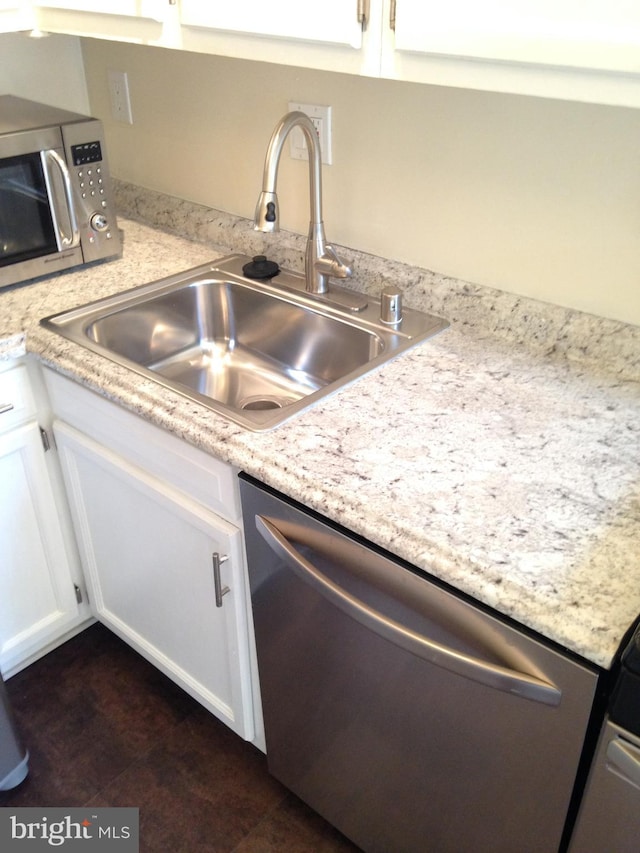 kitchen with appliances with stainless steel finishes, white cabinetry, and sink