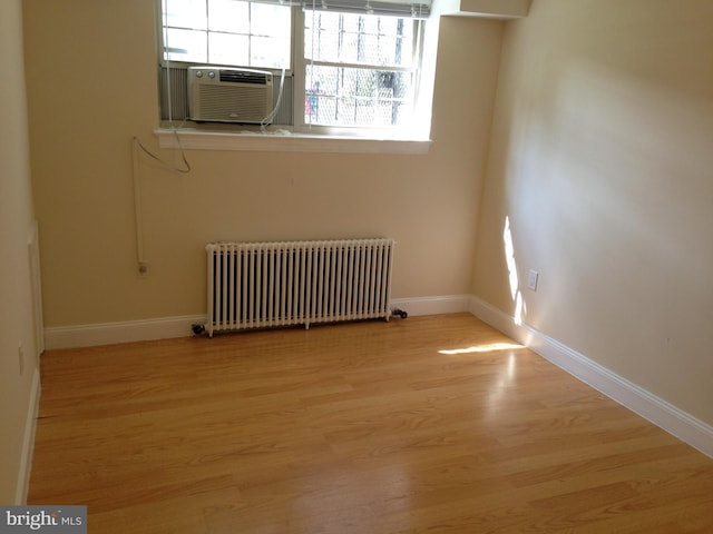 unfurnished room featuring light wood-type flooring, radiator, and cooling unit