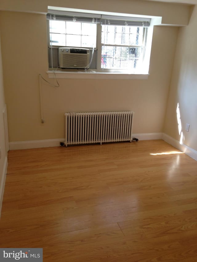 empty room featuring radiator heating unit and light hardwood / wood-style floors