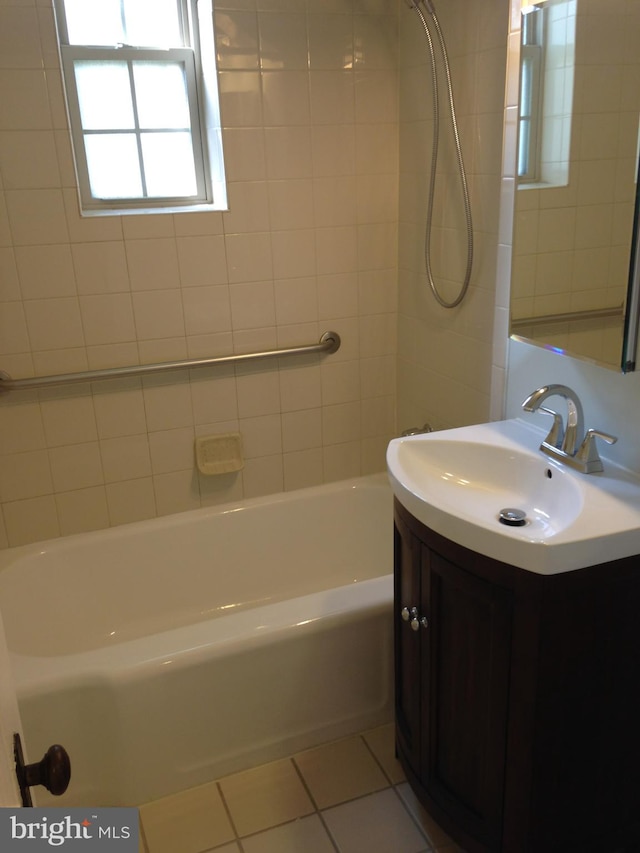 bathroom with tile patterned flooring, vanity, and tiled shower / bath