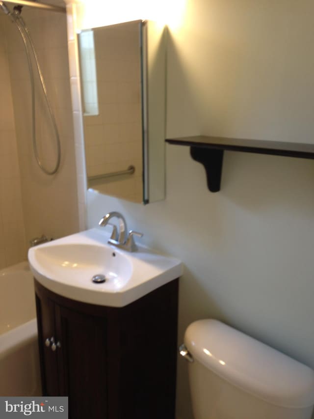 full bathroom featuring vanity, tiled shower / bath combo, and toilet