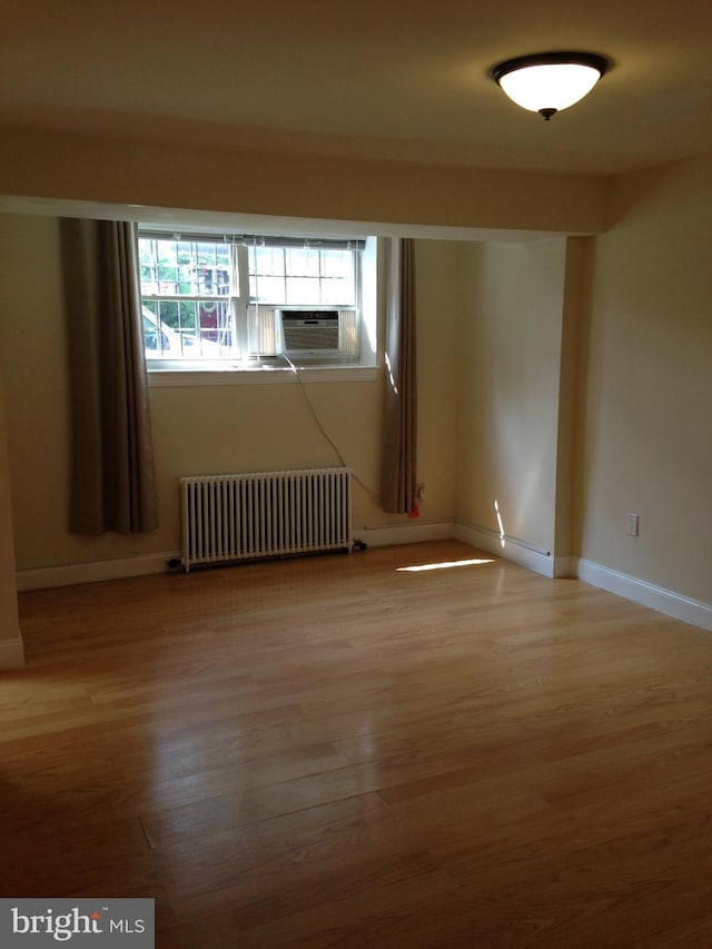 empty room with radiator, cooling unit, and light hardwood / wood-style floors