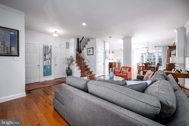 living room with hardwood / wood-style floors, crown molding, and an inviting chandelier