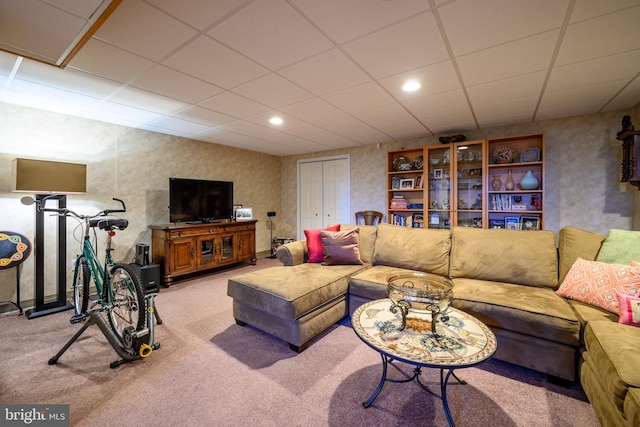 living room featuring a drop ceiling and light carpet